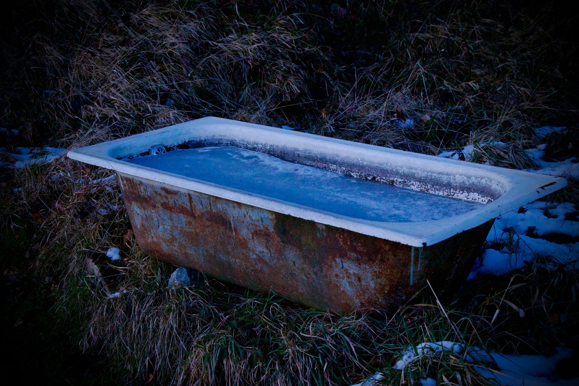 a bathtub sitting in the middle of a field covered in snow